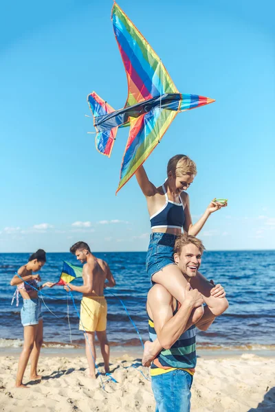 Foco seletivo de grupo interracial de amigos com pipas se divertindo na praia de areia — Fotografia de Stock