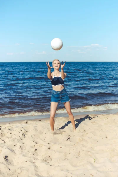 Donna sorridente cattura pallavolo sulla spiaggia il giorno d'estate — Foto stock