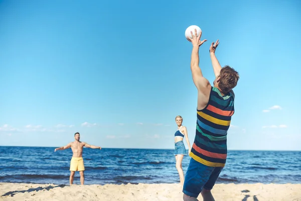 Jóvenes amigos jugando voleibol juntos en la playa de arena - foto de stock