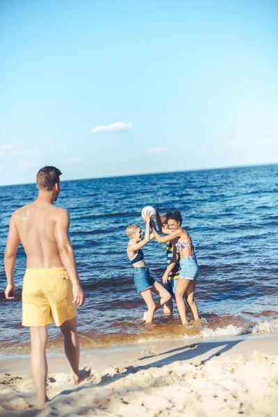 Grupo interracial de amigos com bola de vôlei se divertindo por mar — Fotografia de Stock