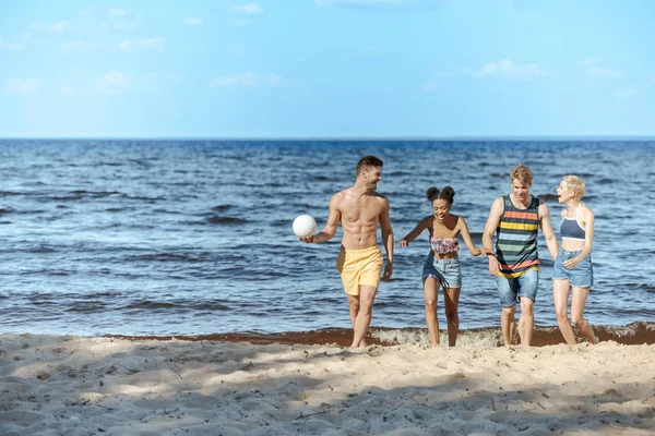 Amici multiculturali con pallavolo passeggiando sulla spiaggia sabbiosa — Foto stock
