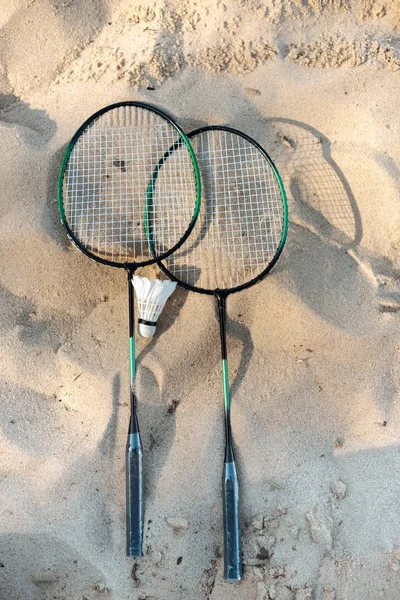 Close up view of badminton racquets and shuttlecock lying on sandy beach — Stock Photo