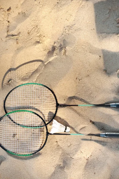 Vue rapprochée des raquettes de badminton et de la navette couchée sur la plage de sable — Photo de stock