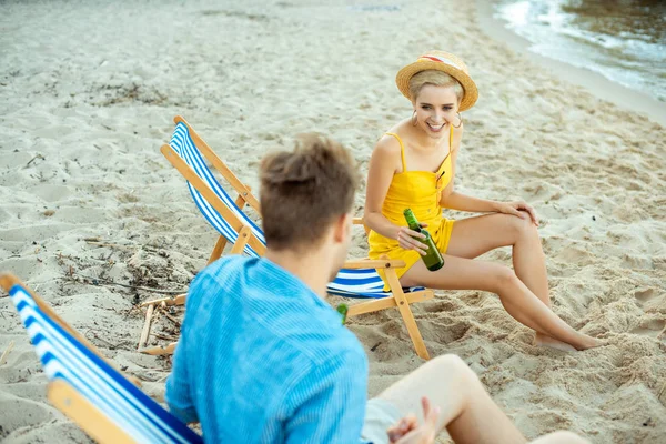 Vue partielle du couple avec de la bière dans des bouteilles en verre reposant dans des chaises de plage le jour d'été — Photo de stock