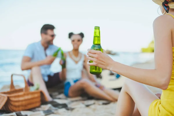 Fuoco selettivo di gruppo di amici con birra che riposa su spiaggia sabbiosa insieme — Foto stock