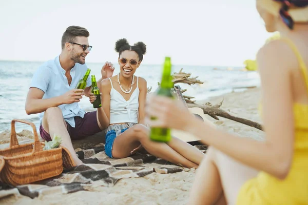 Fuoco selettivo di gruppo di amici con birra che riposa su spiaggia sabbiosa insieme — Foto stock