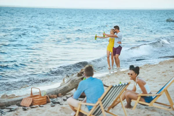 Selektiver Fokus multikultureller junger Freunde mit Bier am Sandstrand — Stockfoto