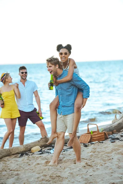 Happy young multicultural friends spending time on beach together on summer day — Stock Photo