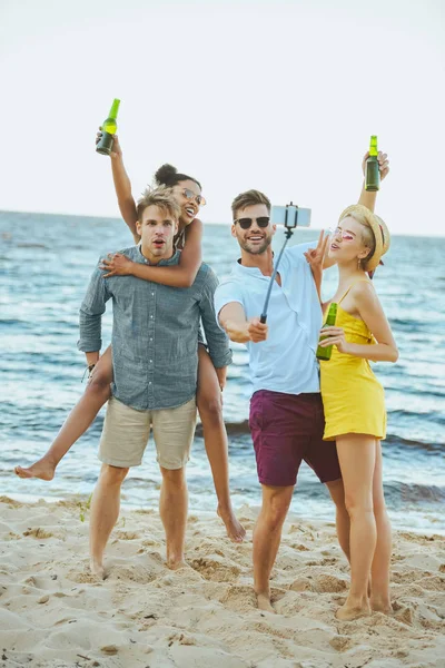 Interracial jeunes amis avec bière prise selfie par la mer — Photo de stock