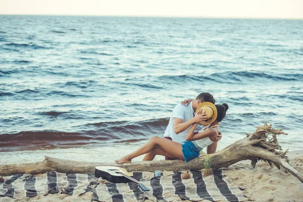 Скрытый вид многонациональной пары, прячущейся за шляпой во время поцелуев на пляже — стоковое фото