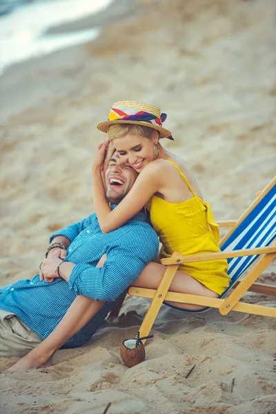 Vista lateral do jovem casal feliz descansando na praia no dia de verão — Fotografia de Stock