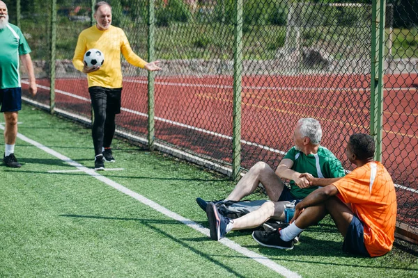 Interracial elderly football players after match on green field — Stock Photo