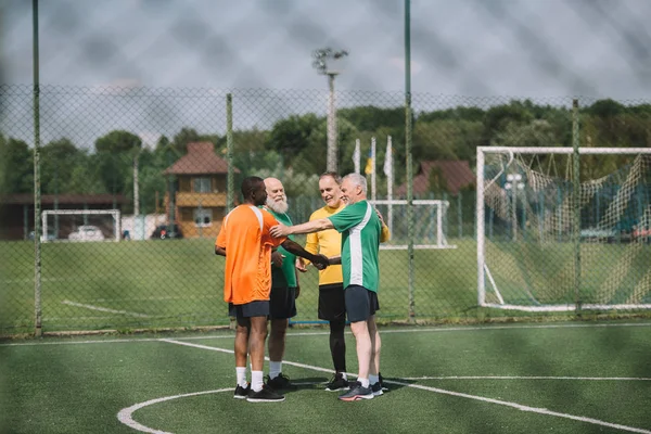 Jugadores de fútbol interracial de edad después del partido en el campo verde - foto de stock