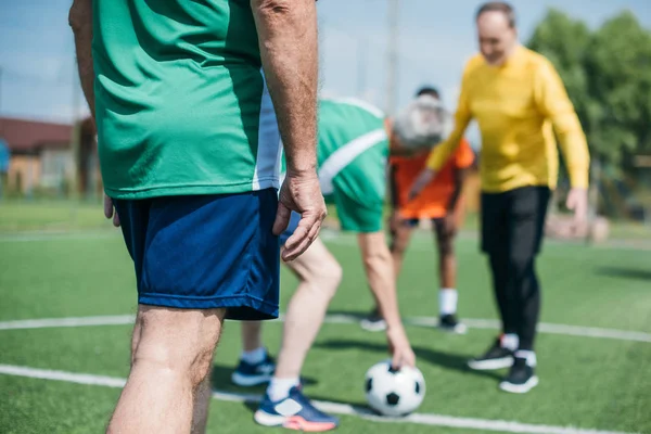 Partial view of multicultural elderly friends playing football together — Stock Photo