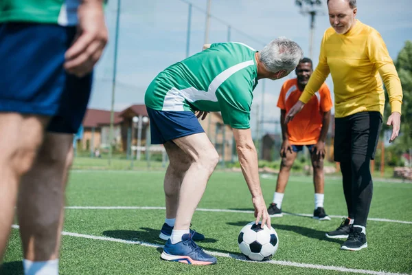 Visão parcial de amigos idosos multiculturais jogando futebol juntos — Fotografia de Stock