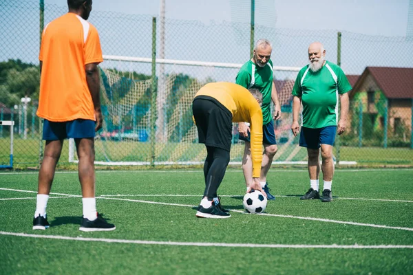 Amigos ancianos multiculturales jugando fútbol juntos - foto de stock