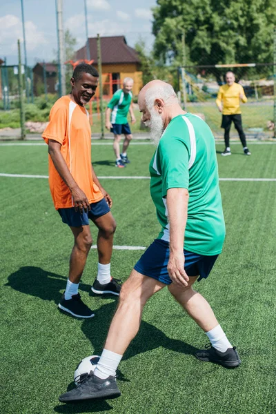 Focus selettivo di amici anziani multiculturali che giocano a calcio insieme — Foto stock