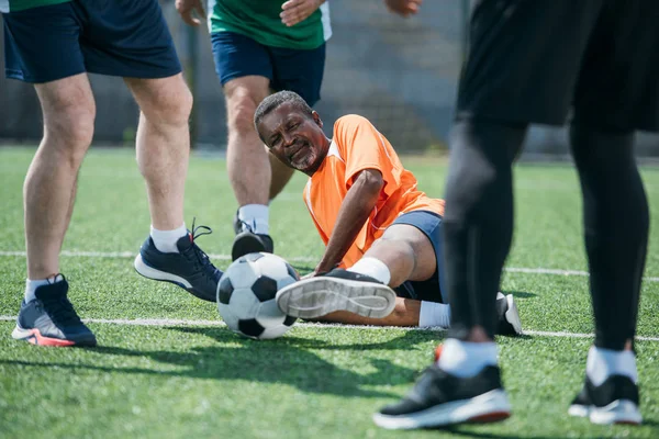 Visión parcial de amigos ancianos multiculturales jugando al fútbol juntos - foto de stock