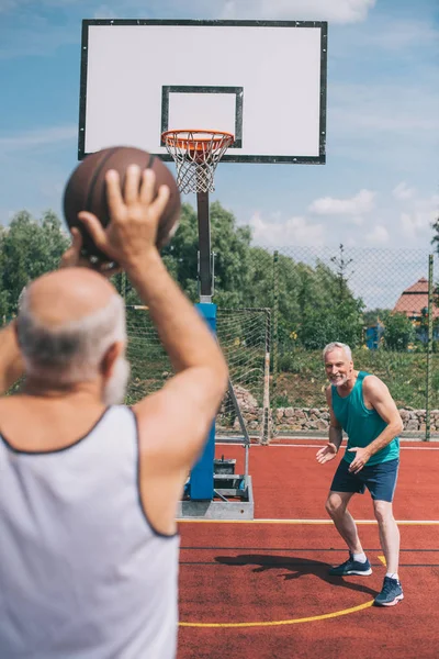 Hommes âgés jouant au basket-ball ensemble sur l'aire de jeux le jour d'été — Photo de stock