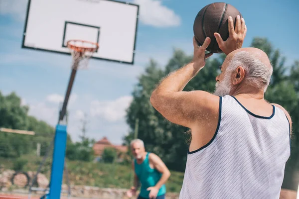 Senioren spielen an Sommertagen gemeinsam Basketball auf Spielplatz — Stockfoto