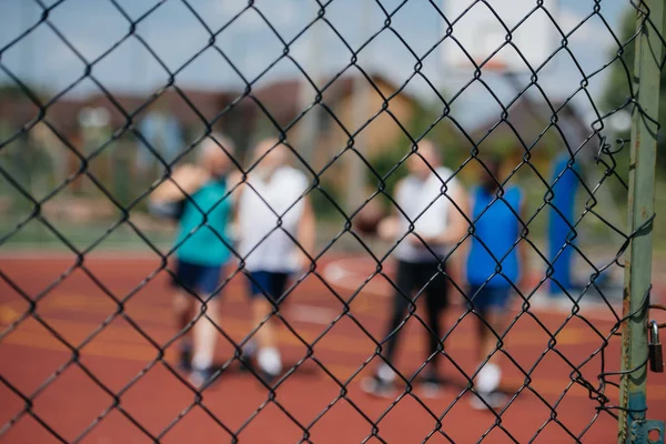 Foco seletivo da rede e dos jogadores no playground de basquete — Fotografia de Stock