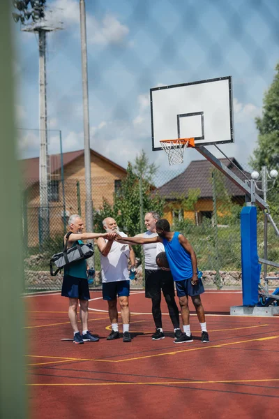 Multiethnic elderly sportsmen with basketball ball on playground — Stock Photo