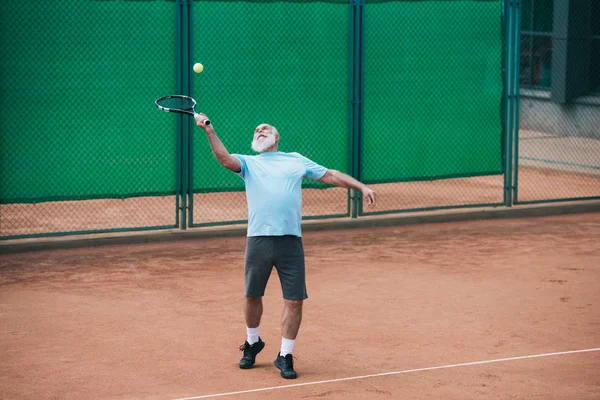 Old man playing tennis on court on summer day — Stock Photo