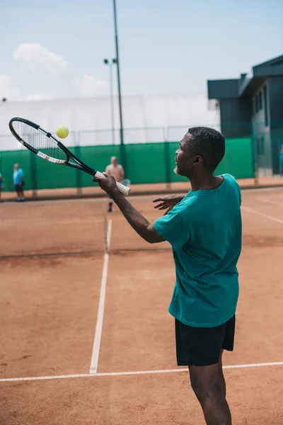 Selective focus of elderly african american man playing tennis with friend on court — Stock Photo