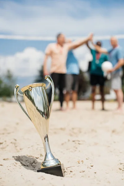 Selective focus of champions cup and volleyball players on beach — Stock Photo