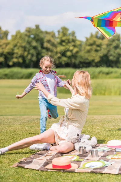 Счастливая мать и дочь проводят время вместе на пикнике в парке — стоковое фото