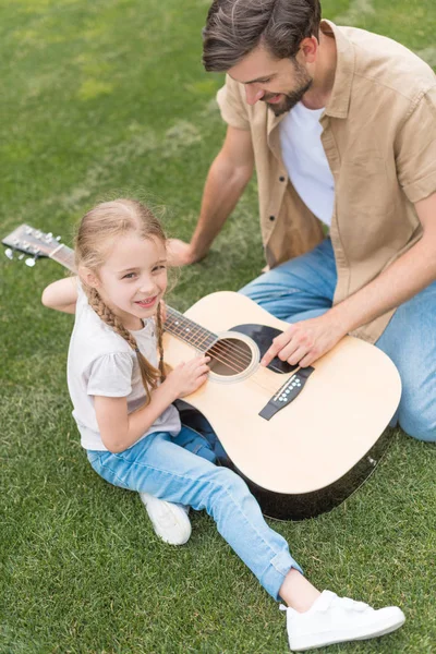 Vista aérea de padre e hija tocando la guitarra acústica en el parque - foto de stock