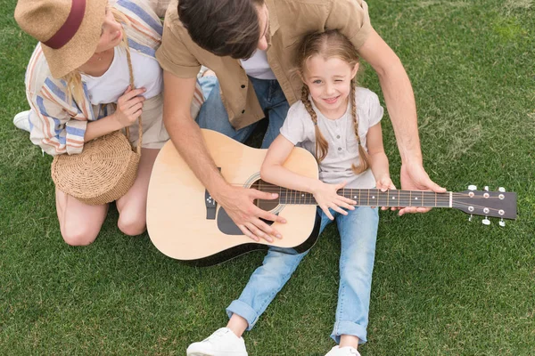 Vue aérienne de la famille avec un enfant jouant de la guitare acoustique sur prairie — Photo de stock