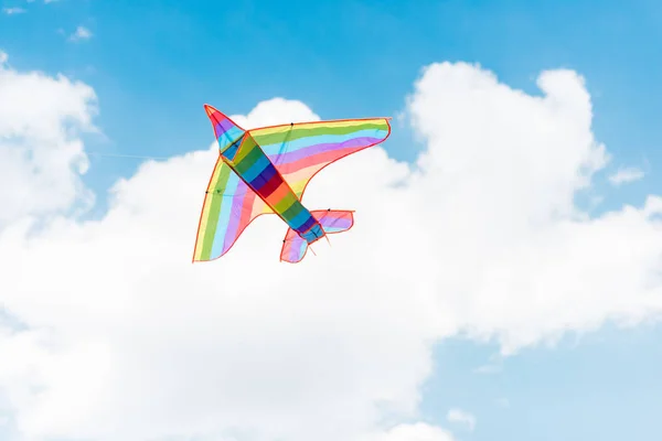 Cometa colorida volando en el cielo azul con nubes - foto de stock