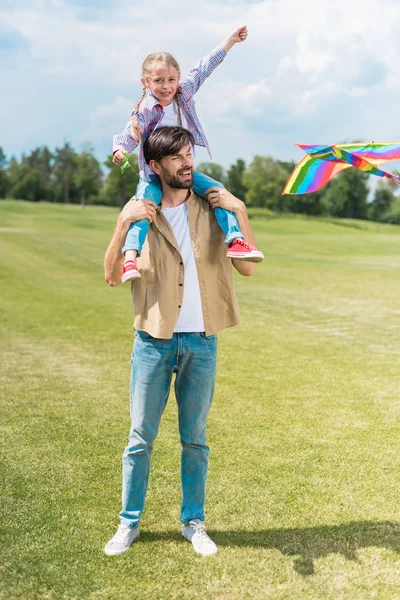 Happy father and daughter playing with colorful kite in park — Stock Photo