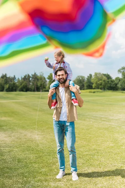Enfoque selectivo de feliz padre e hija jugando con colorido cometa en el parque - foto de stock