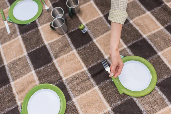 Cropped shot of woman putting cutlery on plaid at picnic — Stock Photo