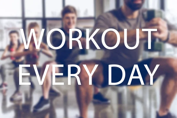 Grupo borroso de jóvenes atléticos en ropa deportiva con pesas haciendo ejercicio en el gimnasio, entrenamiento todos los días inscripción — Stock Photo