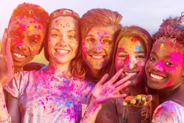 Heureux jeunes amis multiethniques s'amuser avec de la poudre colorée au festival holi et en regardant la caméra — Photo de stock