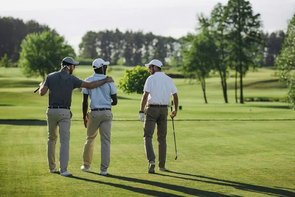 Vue arrière des joueurs de golf multiethniques marchant sur le terrain de golf — Photo de stock