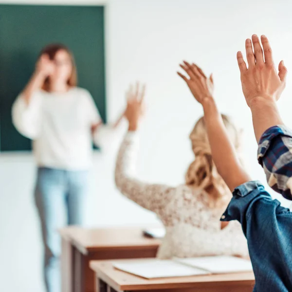 Rückansicht einer Studentengruppe, die in der Vorlesung im Unterricht die Hände hebt — Stockfoto