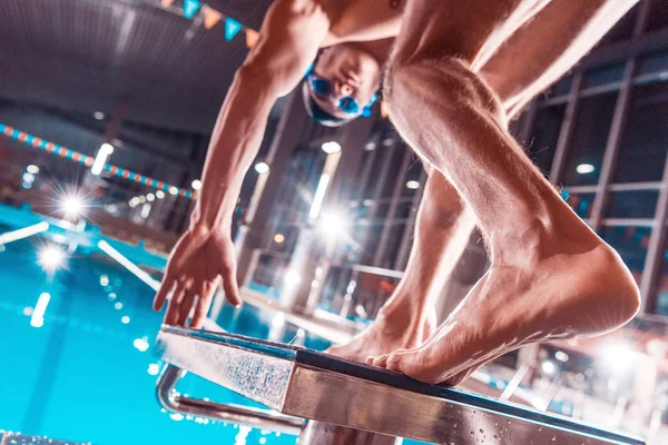 Blick von unten auf athletische männliche Schwimmer, die ins Wettkampfschwimmbecken springen — Stockfoto