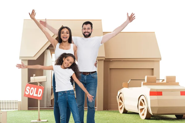 Felice famiglia multietnica con le mani alzate di fronte alla nuova casa — Foto stock
