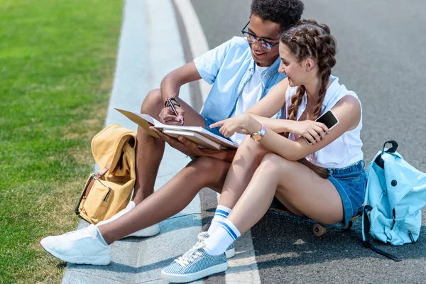 Adolescent multiethnique garçon et fille étudiant ensemble dans le parc — Photo de stock