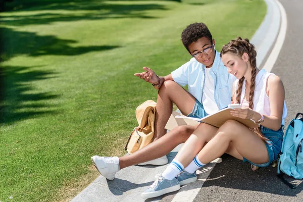 Vista de ángulo alto de adolescente multiétnico y niña estudiando juntos en el parque - foto de stock