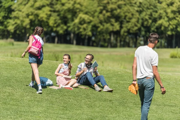 Groupe d'amis adolescents passer du temps ensemble et étudier dans le parc — Photo de stock