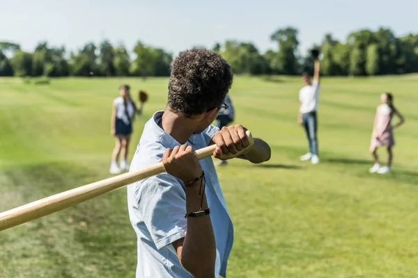 Американский мальчик-подросток играет в бейсбол с друзьями в парке — стоковое фото