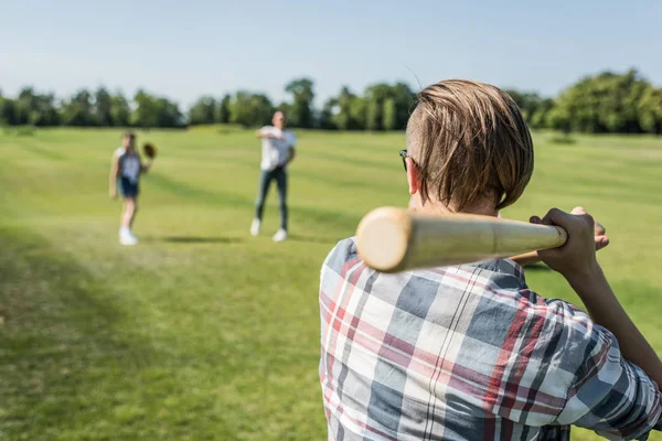 Вид ззаду хлопчика-підлітка, який грає в бейсбол з друзями в парку — стокове фото