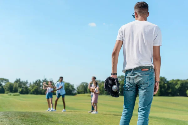 Вид ззаду хлопчика-підлітка, який грає в бейсбол з друзями в парку — стокове фото