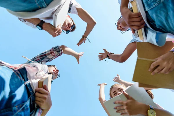 Vista inferior de compañeros de clase adolescentes multiétnicos felices dando cinco en el parque - foto de stock