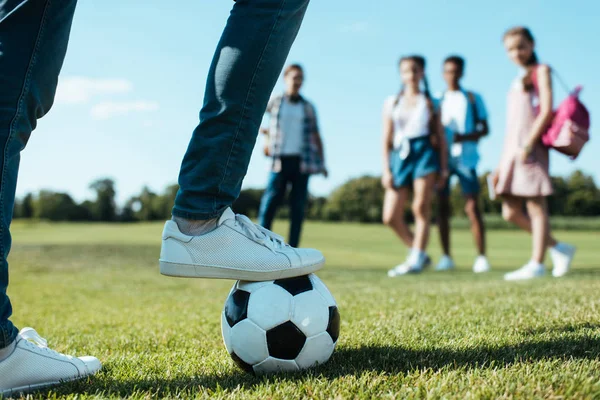 Recortado disparo de adolescentes compañeros de clase jugando con pelota de fútbol en el parque - foto de stock